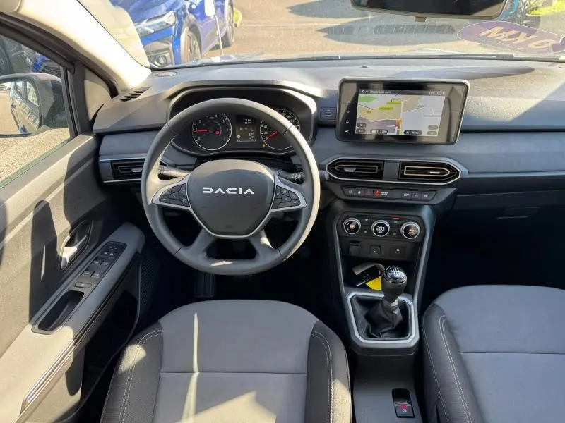 Vue intérieure avant du tableau de bord et volant du Dacia Jogger 2024 avec écran tactile et boîte manuelle.
