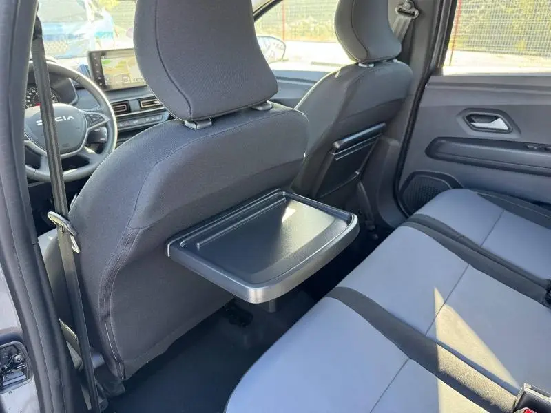 Vue intérieure arrière droite du Dacia Jogger 2024 gris Schiste, avec tablette rabattable sur le dossier avant.