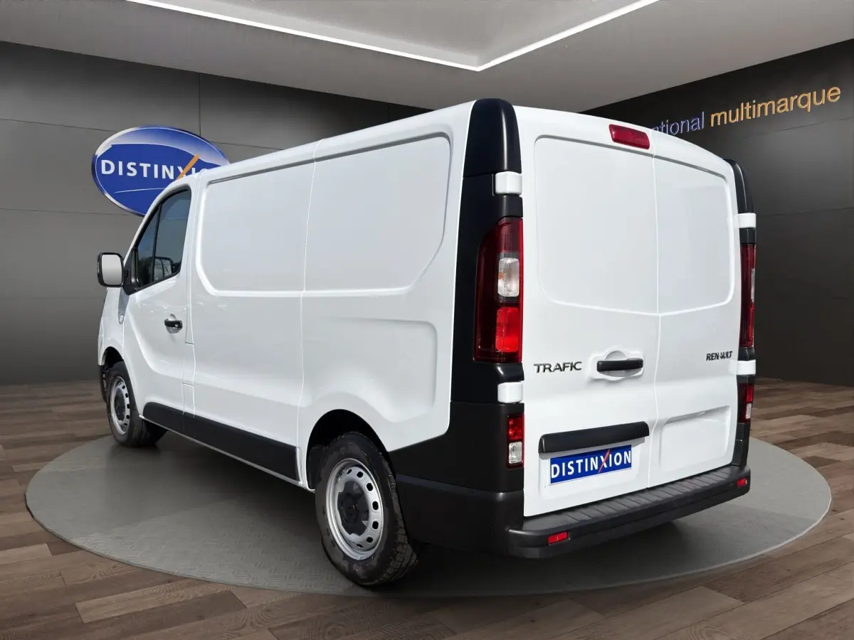 Vue 3/4 arrière droite d’un Renault Trafic Fourgon blanc avec portes arrière pleines et feux verticaux rouges.