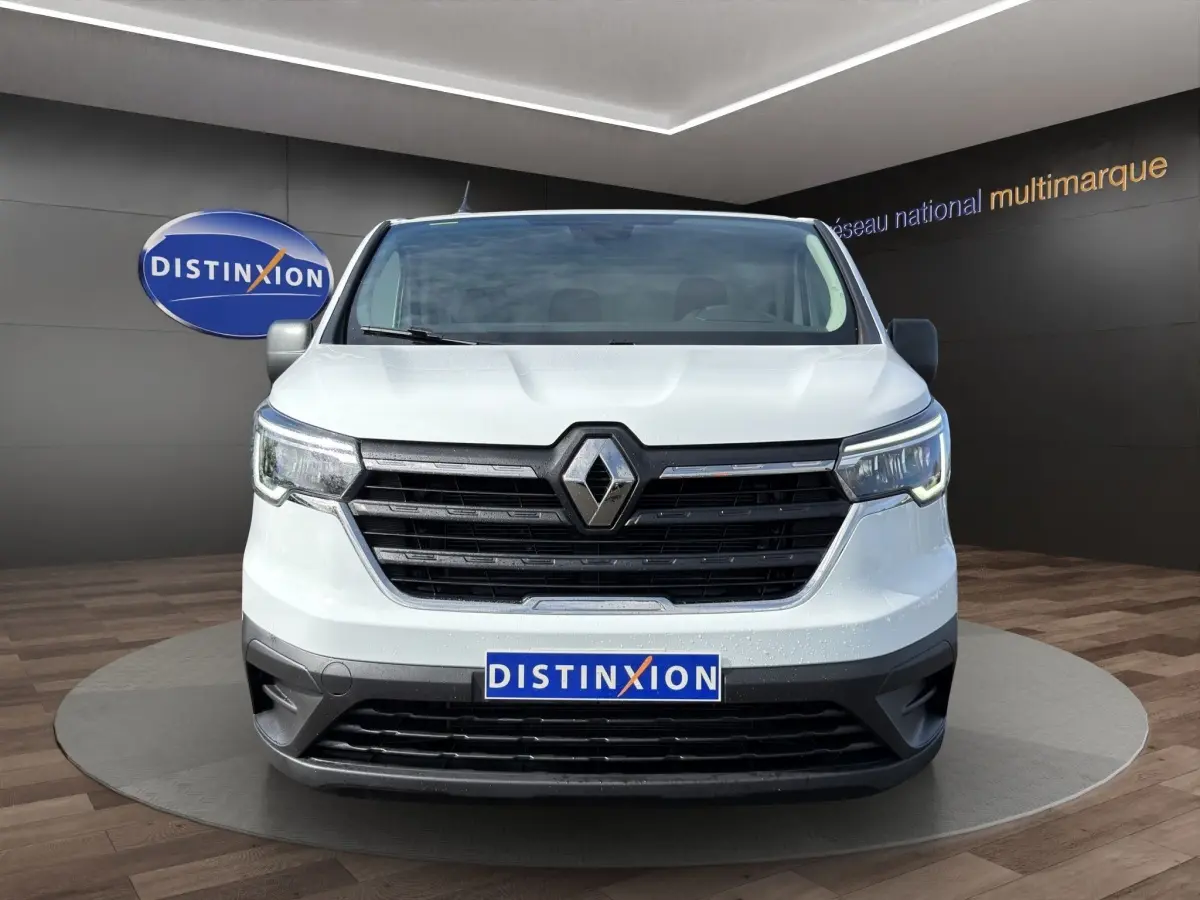 Vue frontale d'un Renault Trafic Fourgon blanc 2024 avec calandre noire et phares LED allumés.