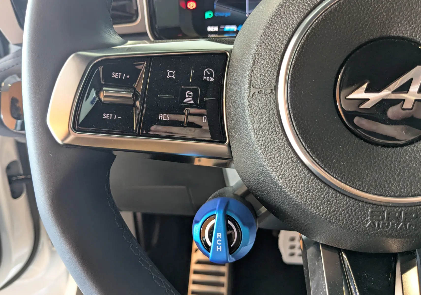 Gros plan sur le volant noir de l'Alpine A290 2026 avec commandes intégrées et sélecteur de mode bleu électrique.