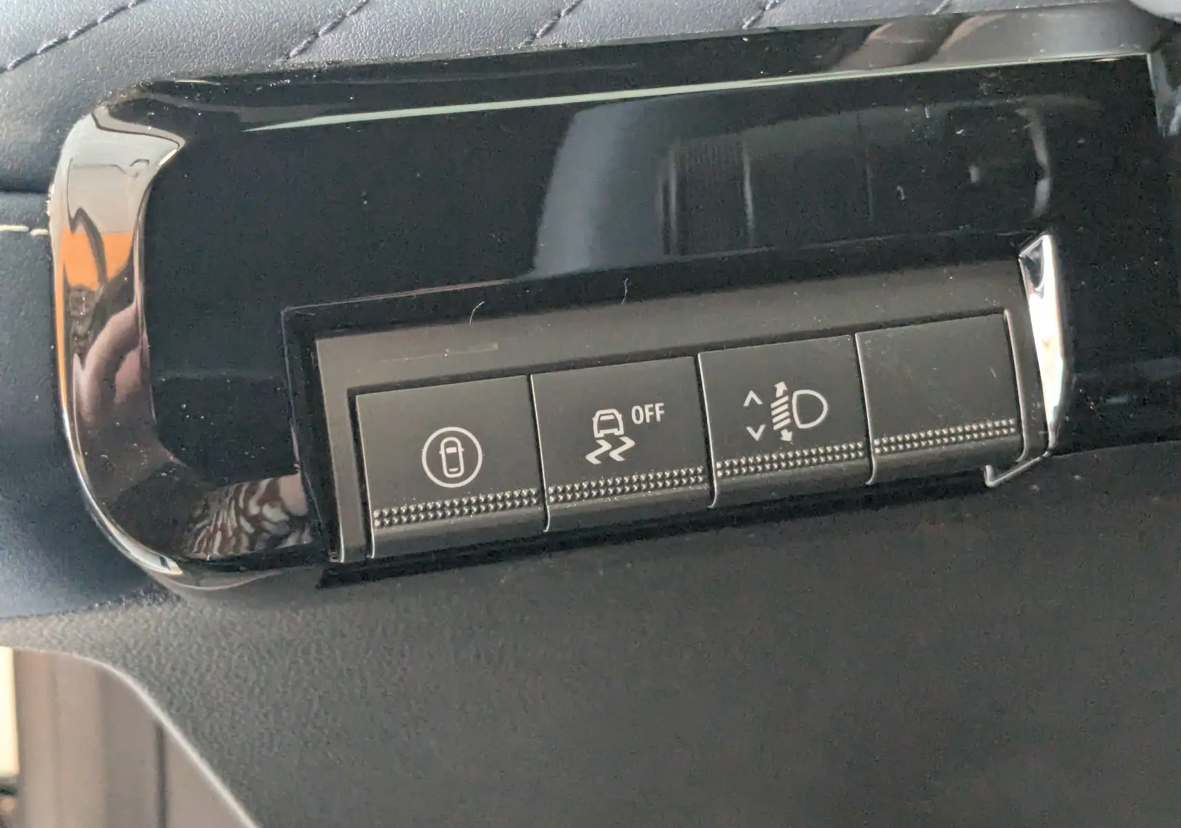 Gros plan sur les boutons de contrôle noirs du tableau de bord de l'Alpine A290, finition brillante et coutures visibles.