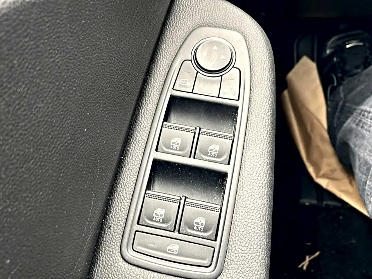Gros plan sur les commandes de lève-vitres électriques côté conducteur d'une Renault Clio V blanche, finition 2025.