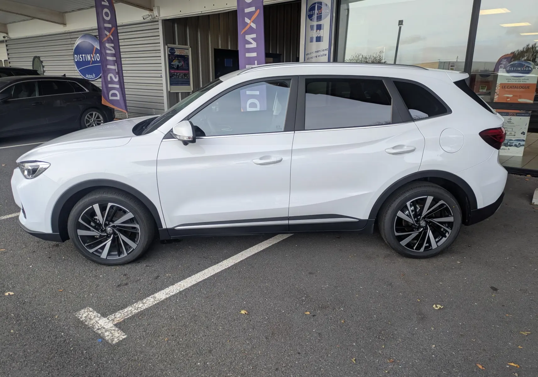 Vue de profil côté gauche d'un MG ZS blanc 2026 avec jantes alliage 18 pouces et toit panoramique.