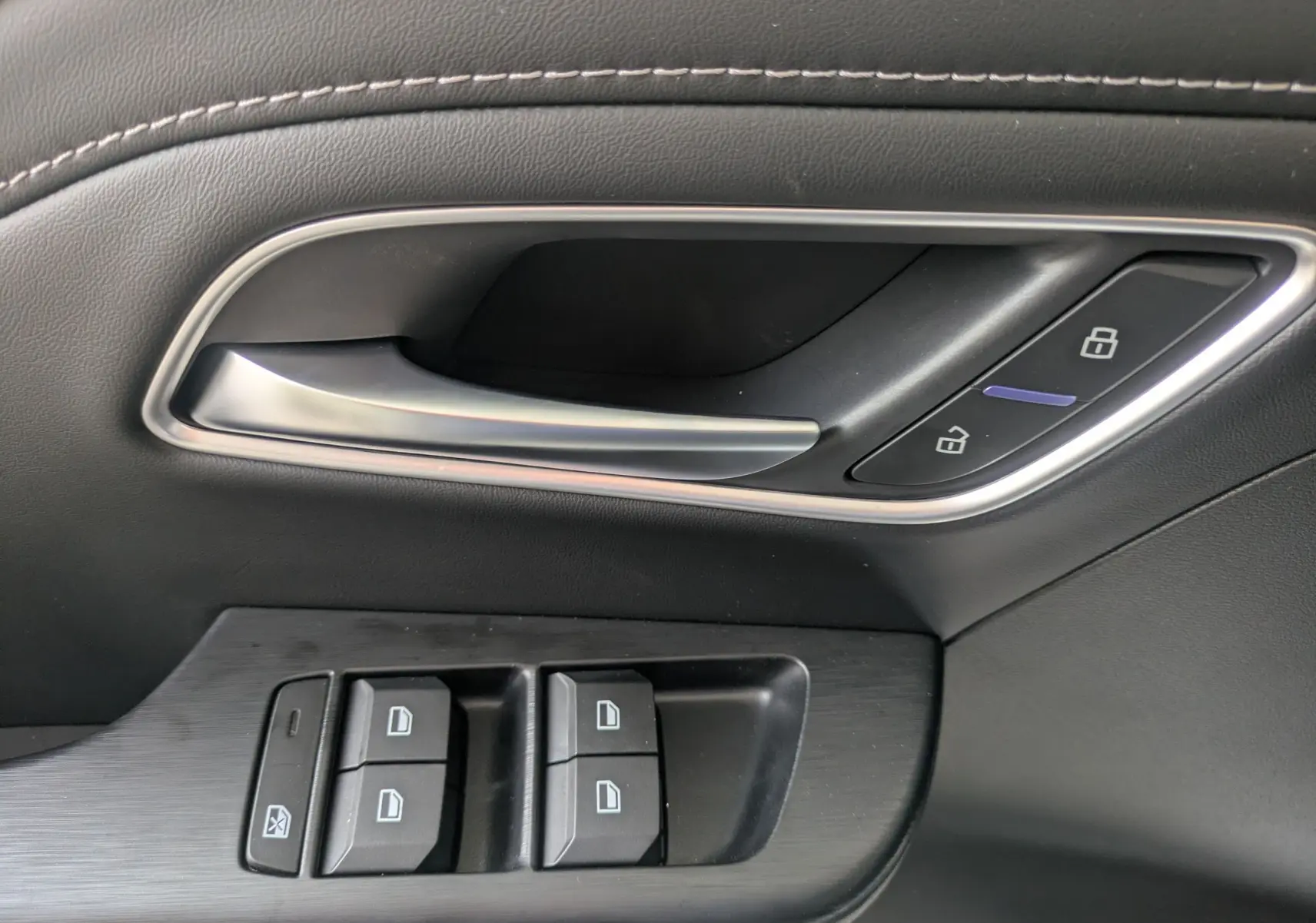 Gros plan sur la poignée intérieure et les commandes de fenêtre côté conducteur du MG ZS blanc 2026.