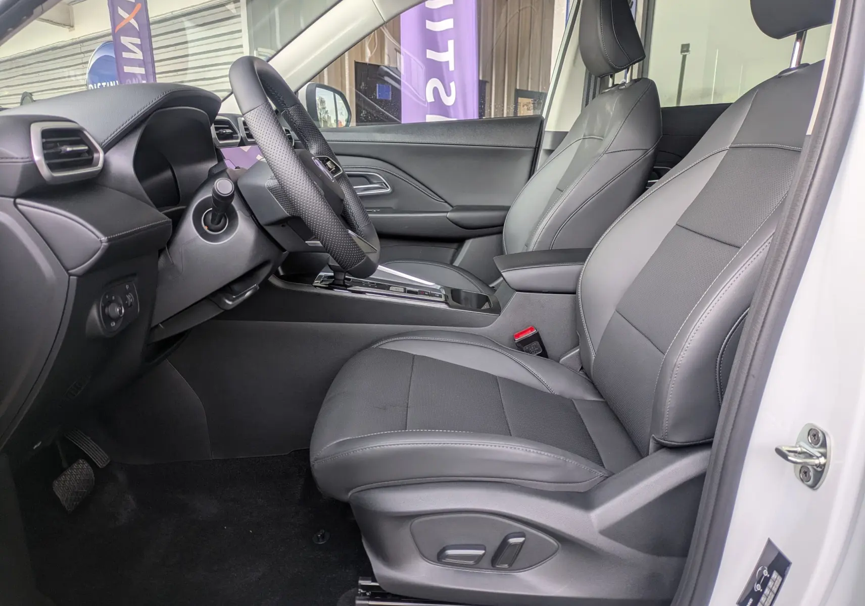 Vue intérieure côté conducteur du MG ZS blanc 2026, sièges en similicuir noir perforé avec réglages électriques et volant cuir.