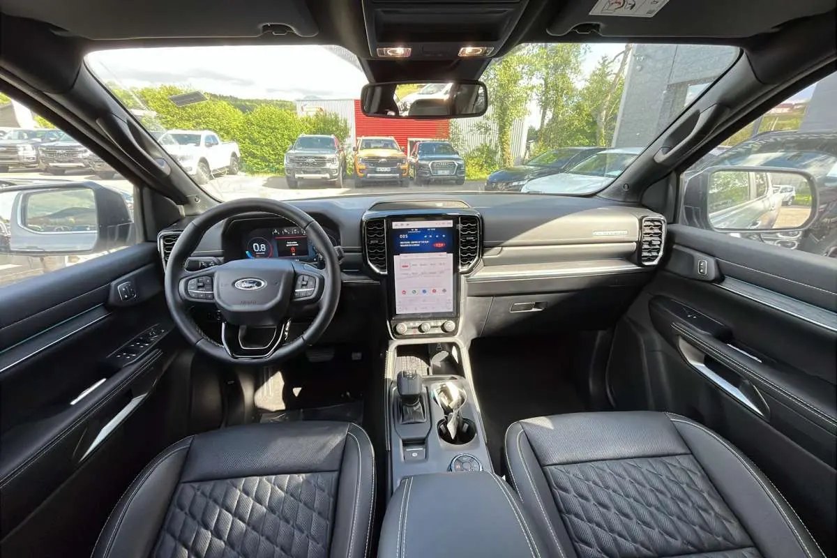 Vue intérieure avant du Ford Ranger 2026, tableau de bord et sièges en cuir noir avec écran tactile vertical central.