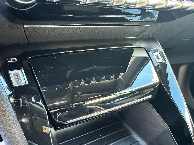 Gros plan sur la console centrale noire brillante du Peugeot 2008 1.2 PureTech 130ch GT, avec ports USB visibles.
