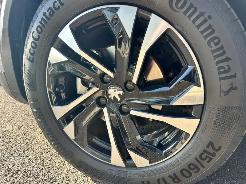 Gros plan sur la jante alu noire et argentée du Peugeot 2008 gris Artense avec pneu Continental Ecocontact.