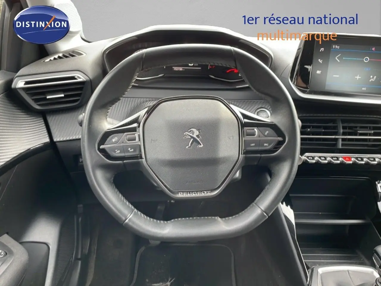 Vue intérieure centrée sur le volant Peugeot d'une 208 rouge Elixir 2022, avec tableau de bord et écran tactile visibles.