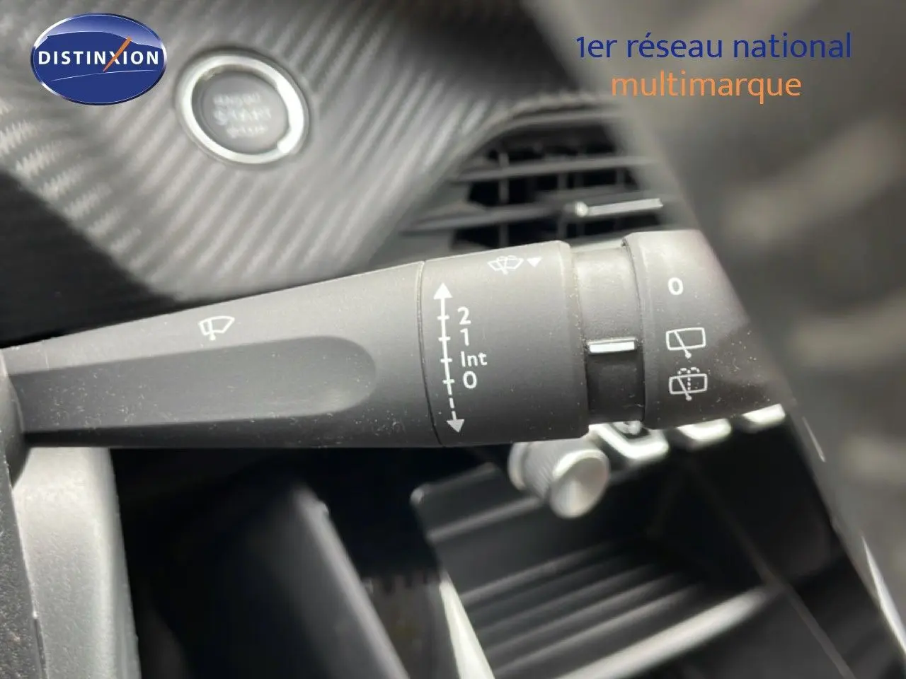 Gros plan sur la commande d’essuie-glace à gauche du volant dans l’habitacle d’une Peugeot 208 rouge Elixir Metal.