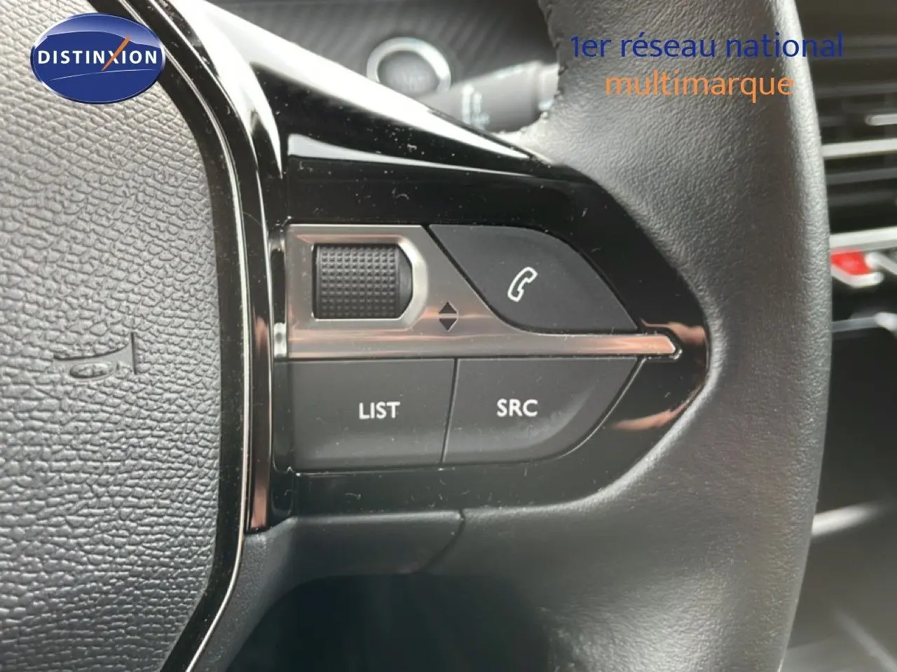 Gros plan sur les commandes gauche du volant en cuir noir de la Peugeot 208, boutons pour appels et audio.
