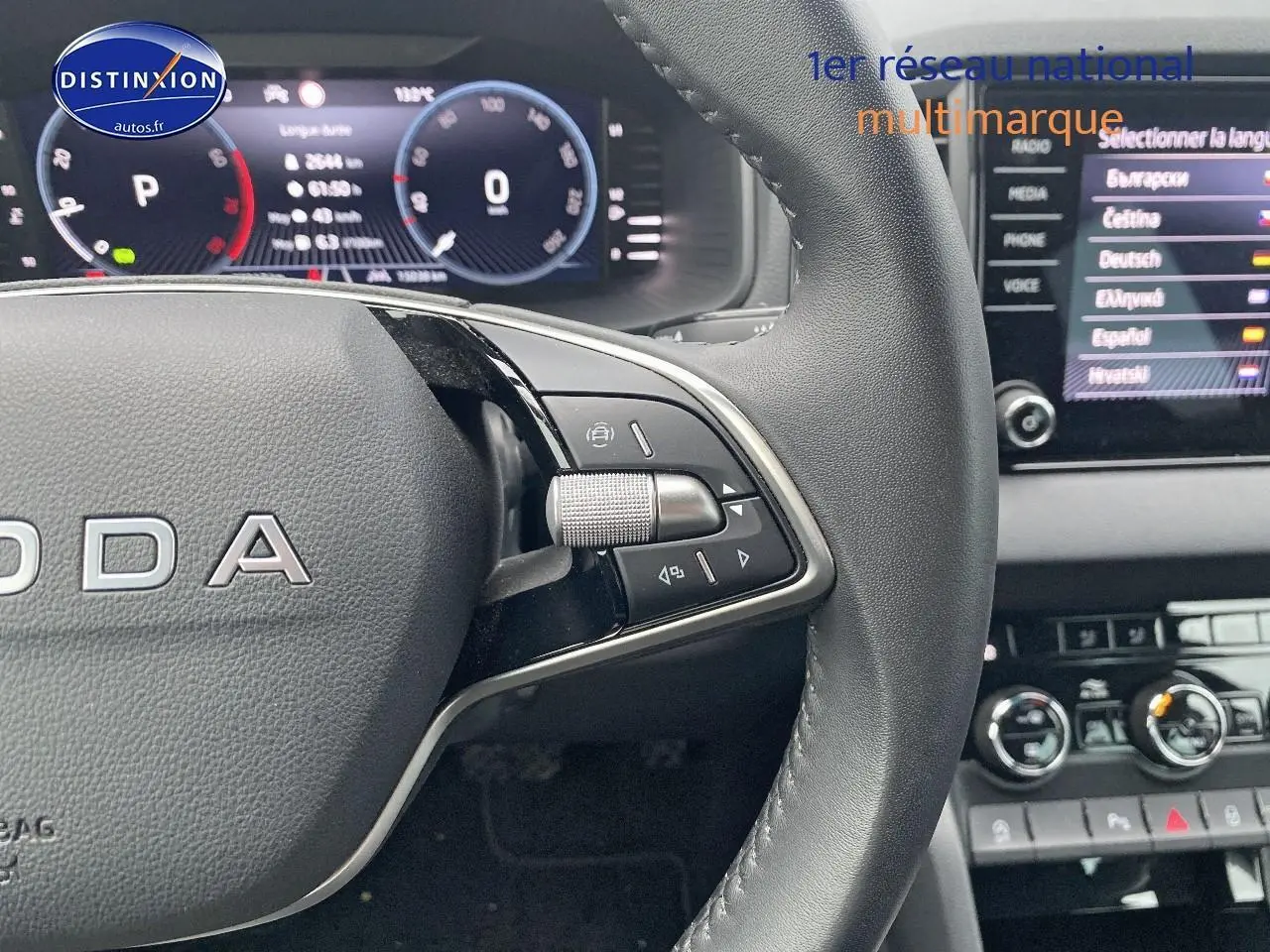 Gros plan sur le volant cuir multifonction noir d’un Skoda Karoq 1.5 TSI 2025 avec tableau de bord digital et écran tactile.