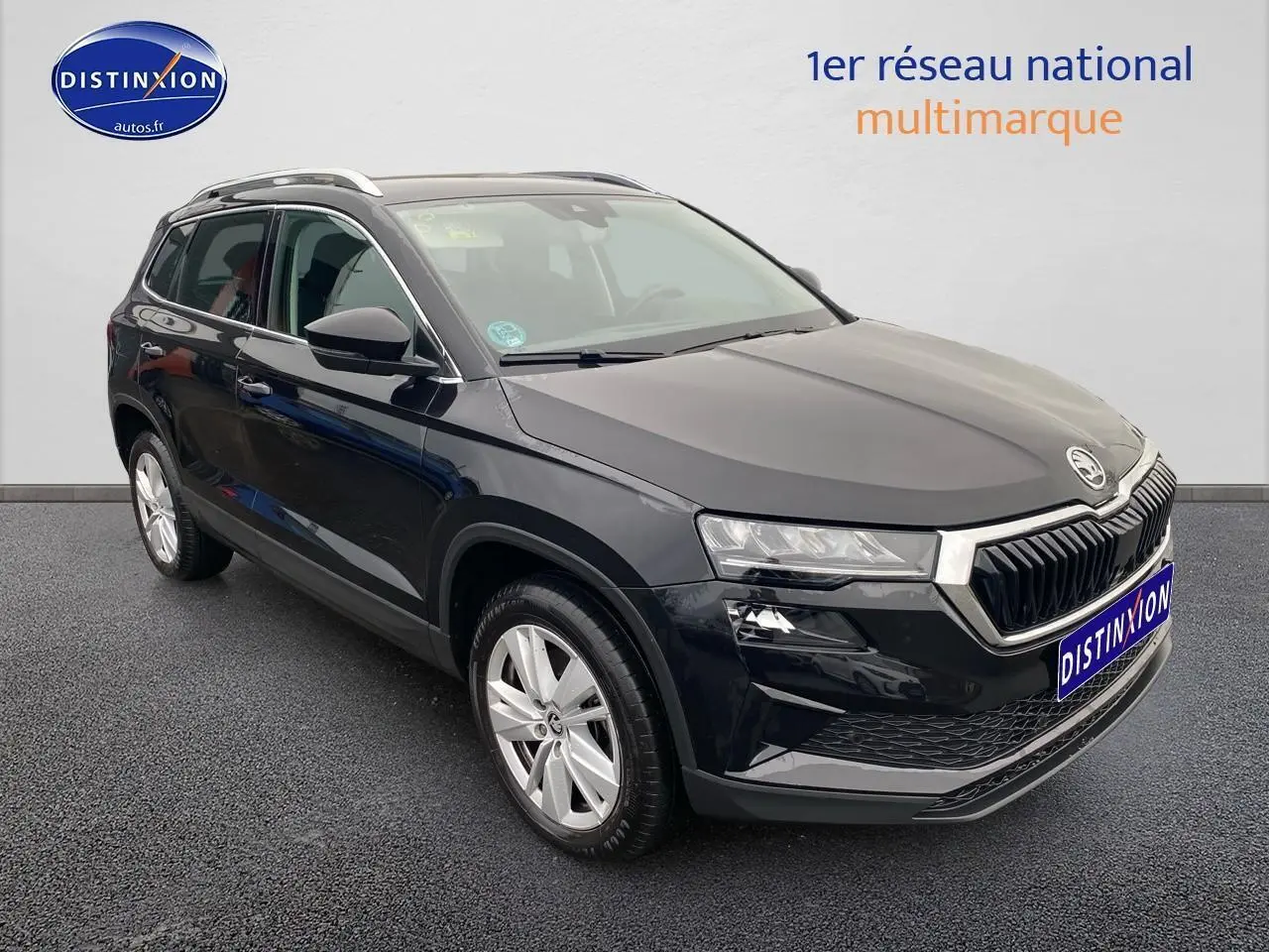 Vue 3/4 avant droit d'un Skoda Karoq noir 2025 avec jantes alu et barres de toit visibles.