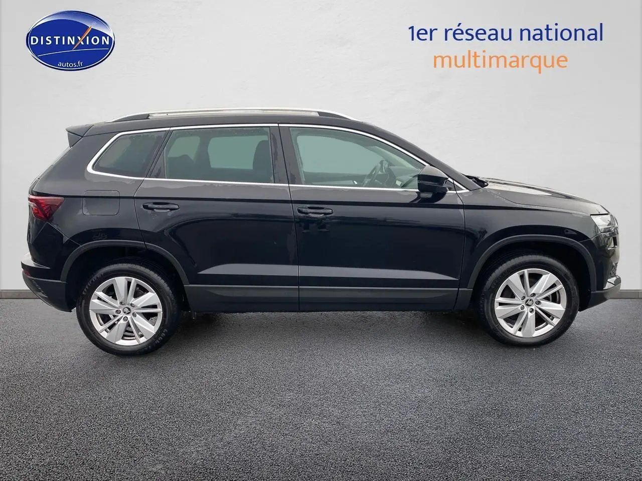 Profil côté droit du SUV SKODA KAROQ noir 2025 avec jantes alu et barres de toit visibles sur fond neutre.