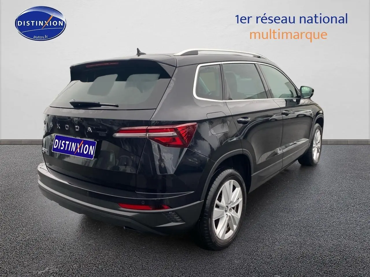 Vue 3/4 arrière droite d'un Skoda Karoq noir 2025 avec jantes alu et barres de toit argentées.