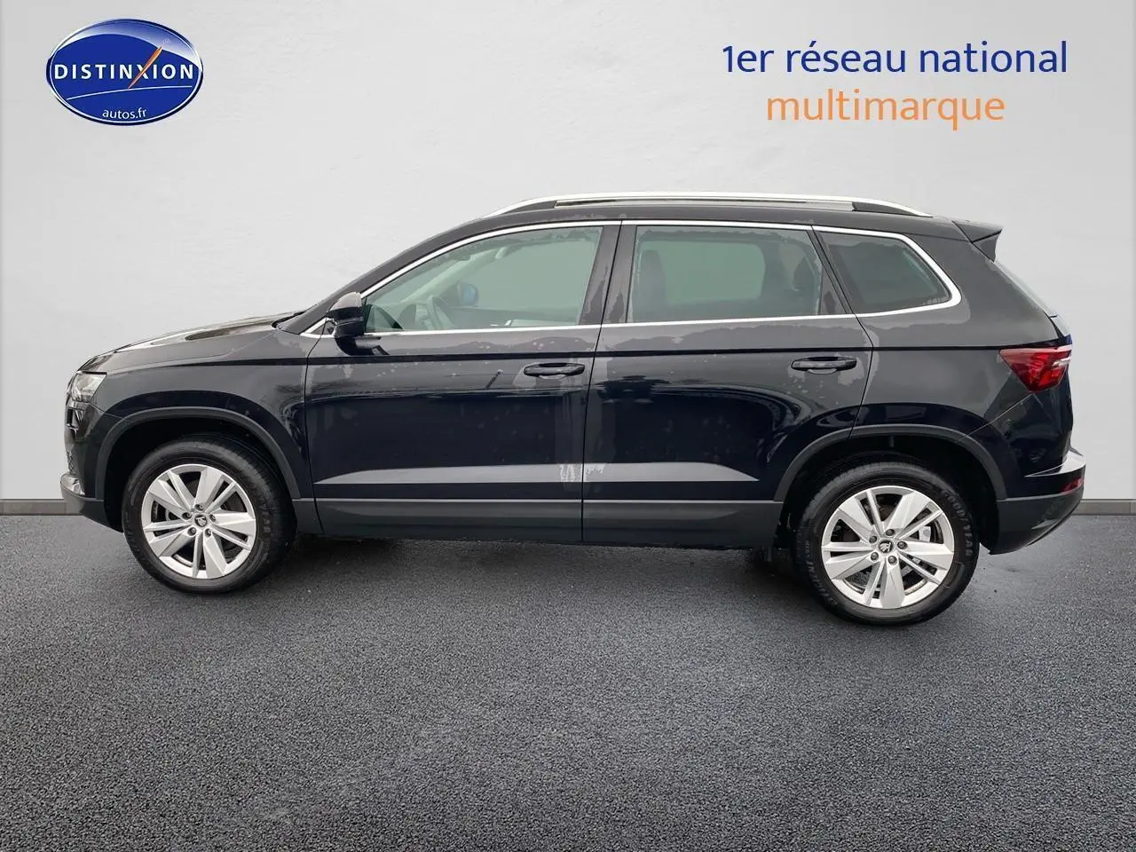 Vue de profil côté gauche d'un Skoda Karoq noir 2025 avec jantes alu et barres de toit visibles.