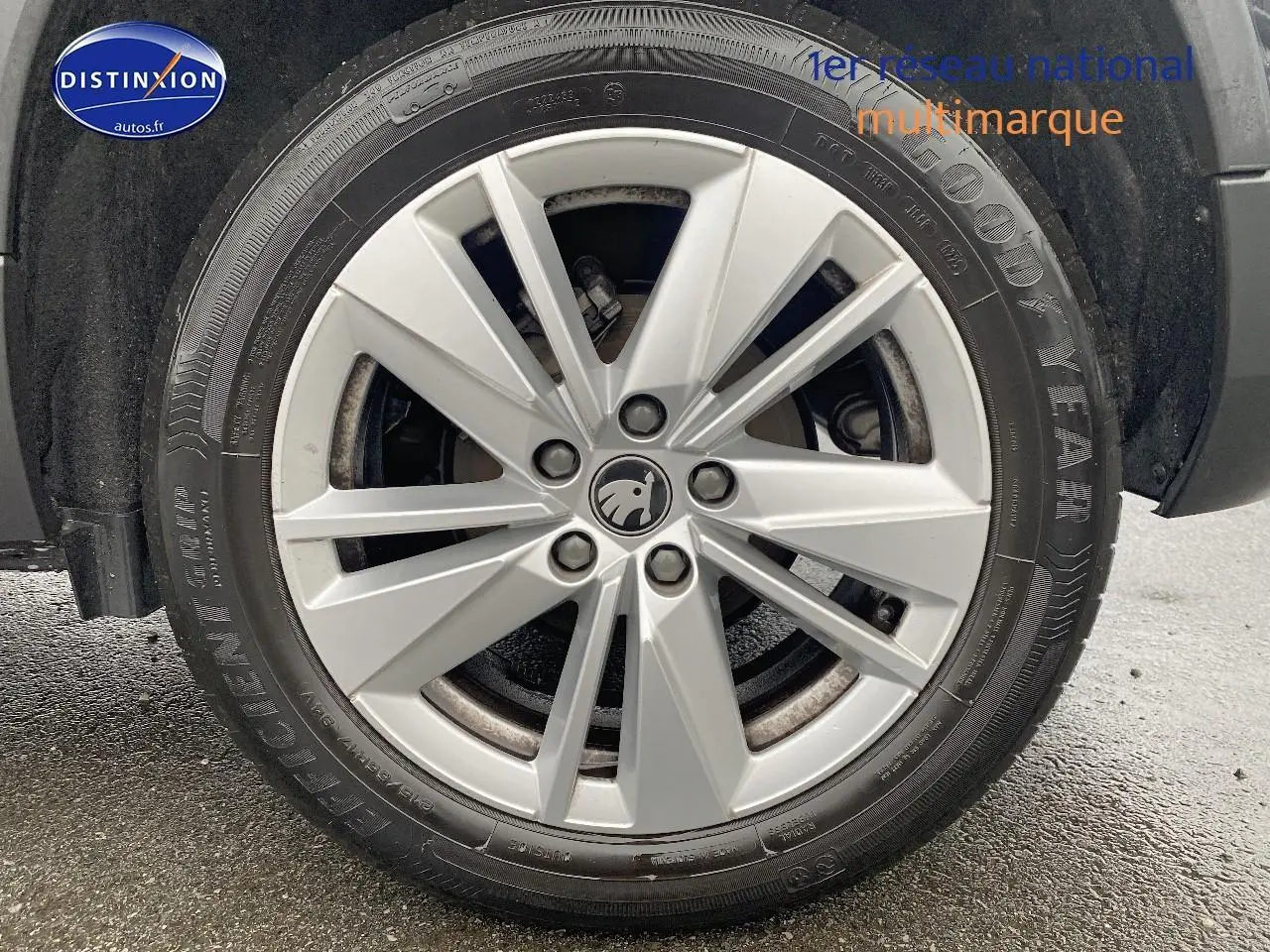 Gros plan sur la jante alu argentée avec logo SKODA d'un SUV noir, vue côté droit, pneu Goodyear visible.