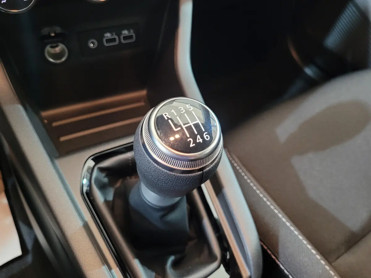 Gros plan sur le levier de vitesses manuel de la Renault Clio gris foncé, avec console centrale et sièges partiellement visibles.