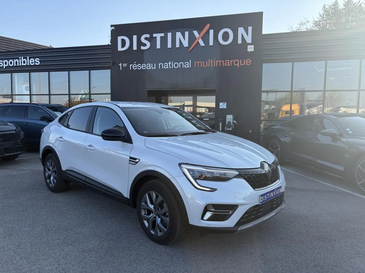 Renault Arkana blanc glacier en 3/4 avant droit, avec jantes alliage grises et rétroviseurs noirs.