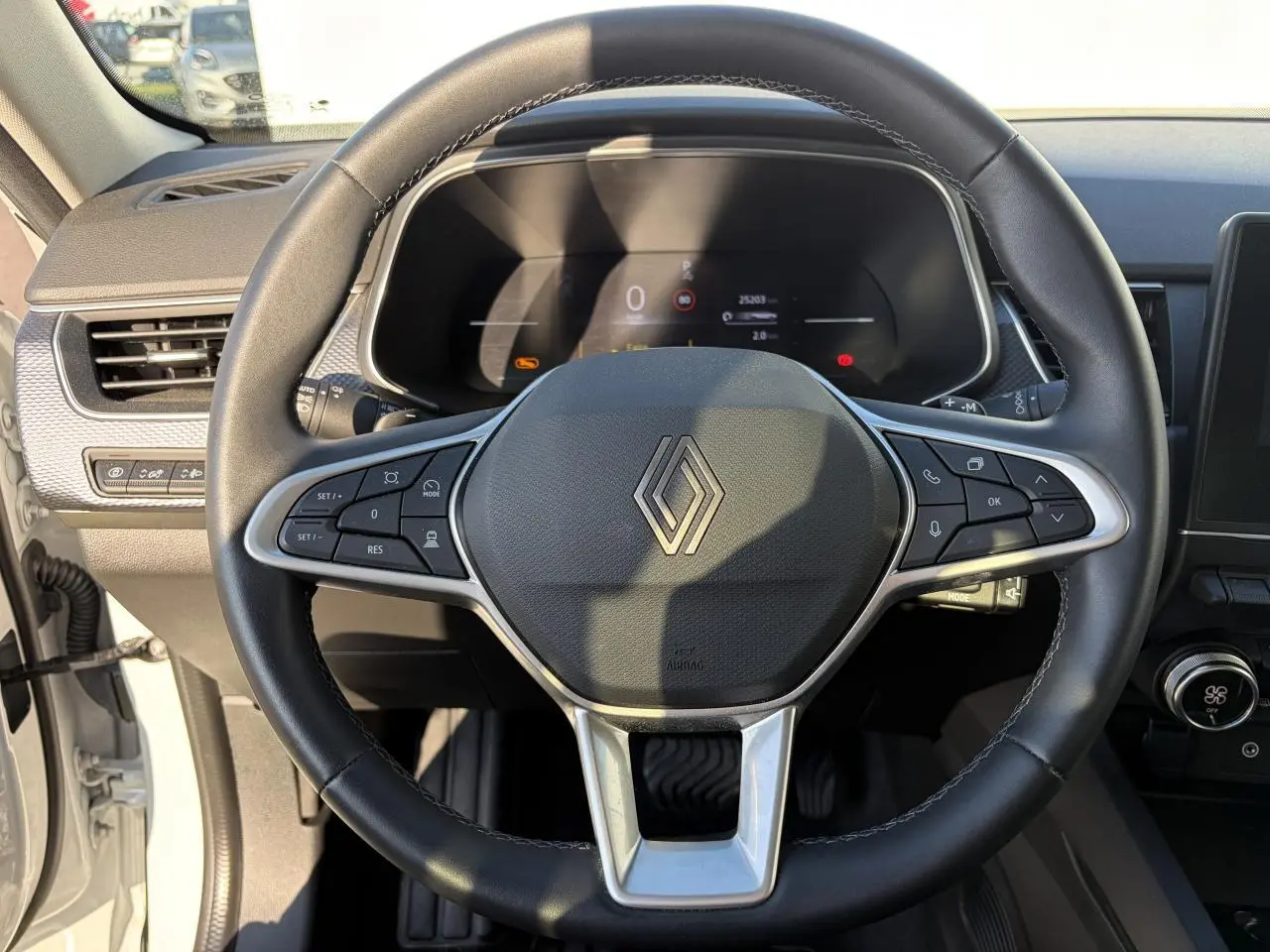 Vue rapprochée du volant noir de la Renault Arkana 2025 avec commandes intégrées et tableau de bord numérique.