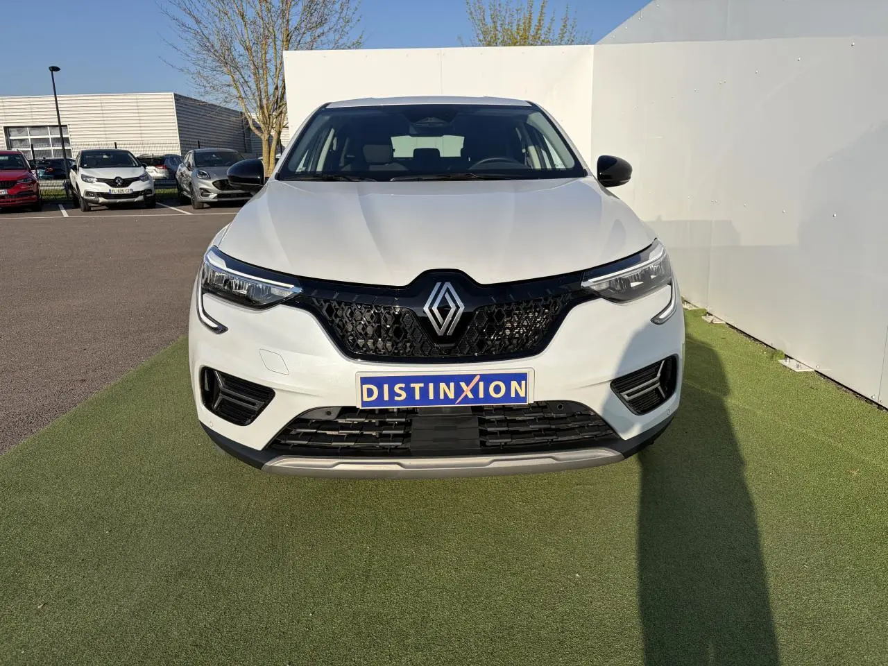 Vue frontale du Renault Arkana blanc glacier 2025 avec calandre noire et phares LED distinctifs.