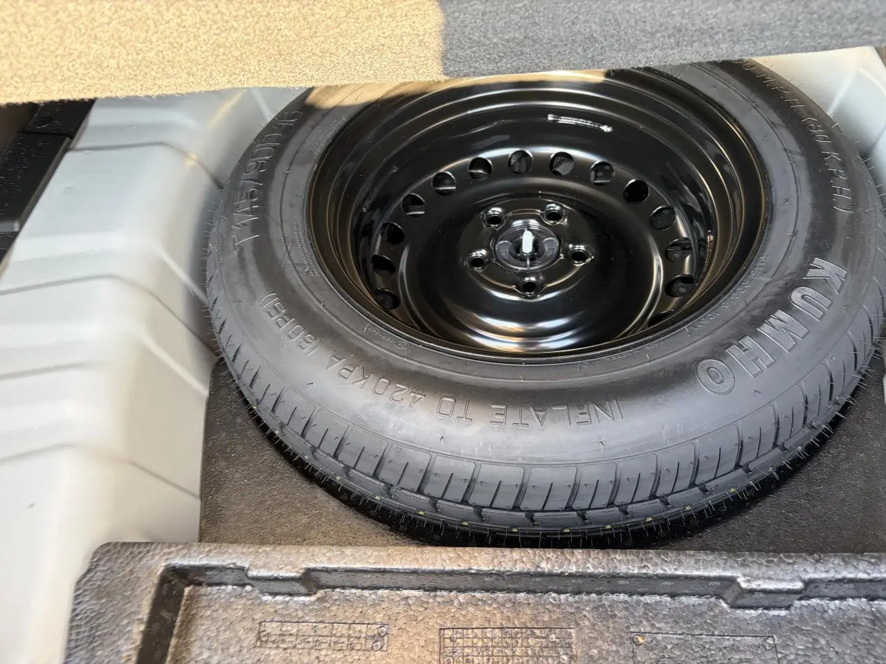 Vue rapprochée de la roue de secours noire dans le coffre d’un Renault Arkana Blanc Glacier 2025.