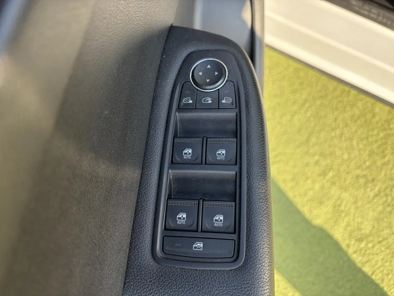 Gros plan sur les commandes des vitres électriques côté conducteur du Renault Arkana blanc glacier 2025.