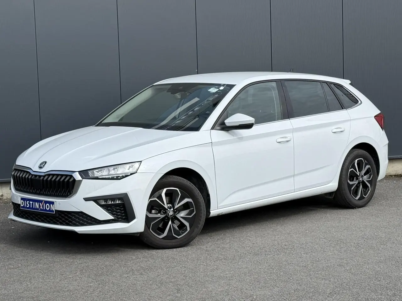 Vue 3/4 avant droite d'une Skoda Scala blanche Glacier avec jantes alliage et vitres surteintées.