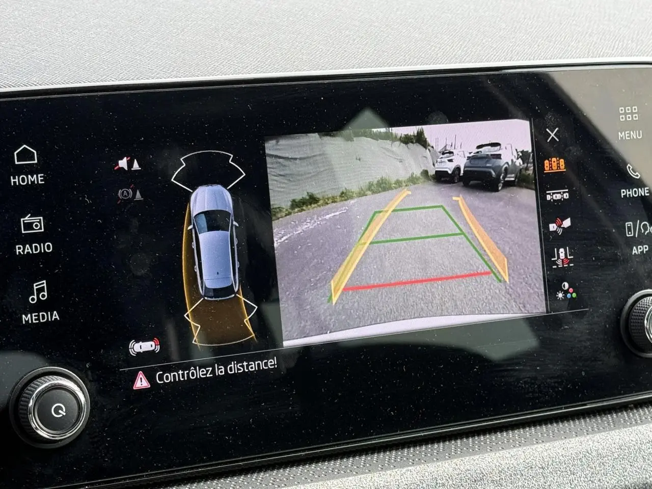 Écran tactile intérieur montrant la caméra de recul active d'une Skoda Scala blanche Glacier en stationnement.