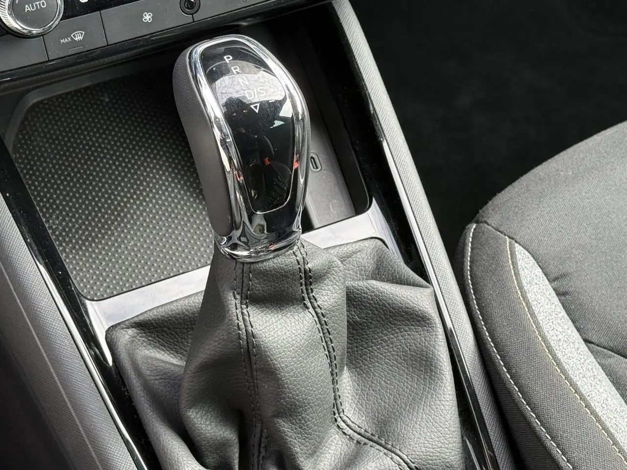 Le levier de vitesses automatique chromé et noir de la Skoda Scala TSI 116 DSG7, avec console et siège tissu gris.