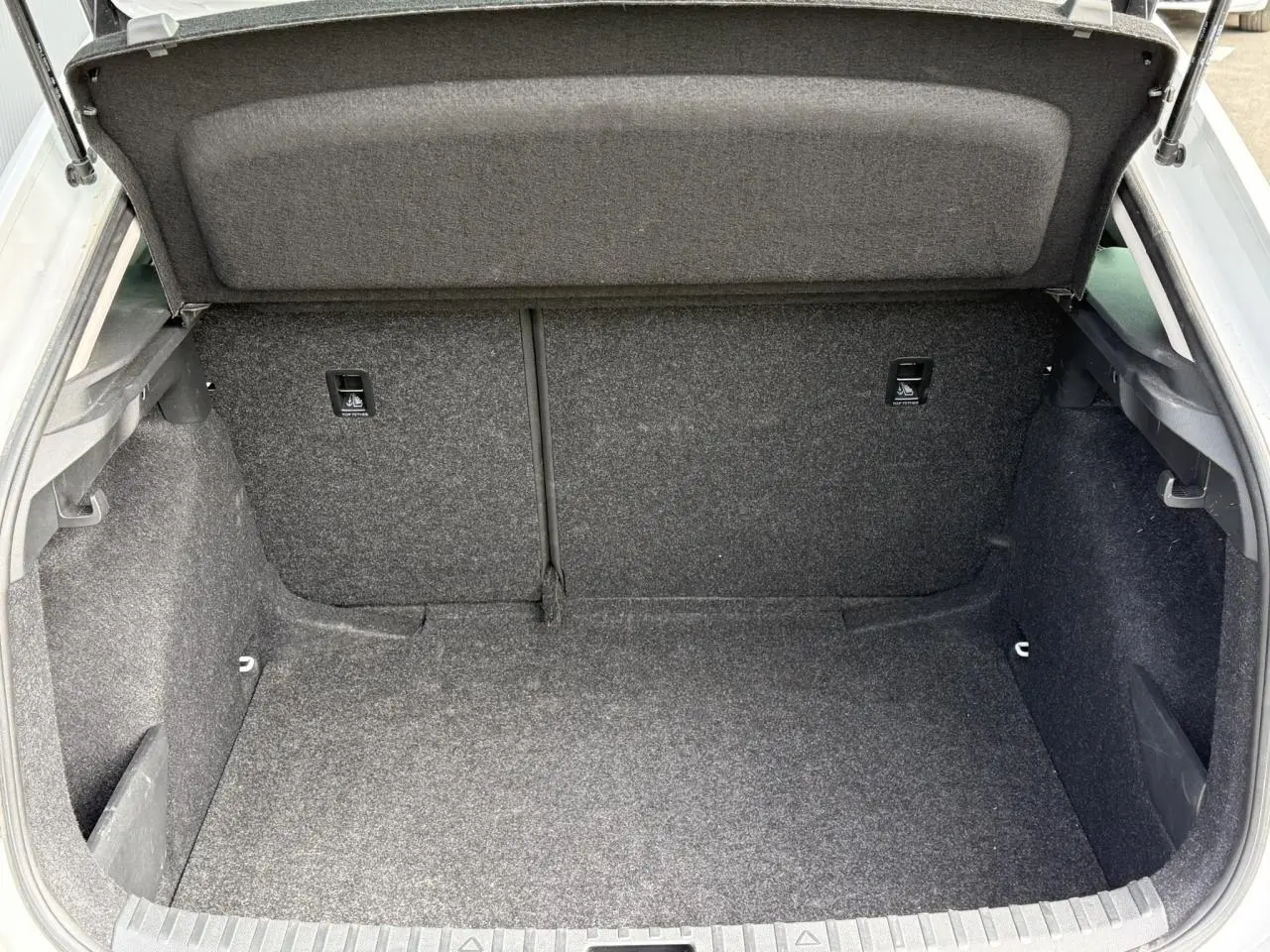 Coffre ouvert de la Skoda Scala blanc Glacier, vue intérieure montrant un espace de chargement propre et spacieux.
