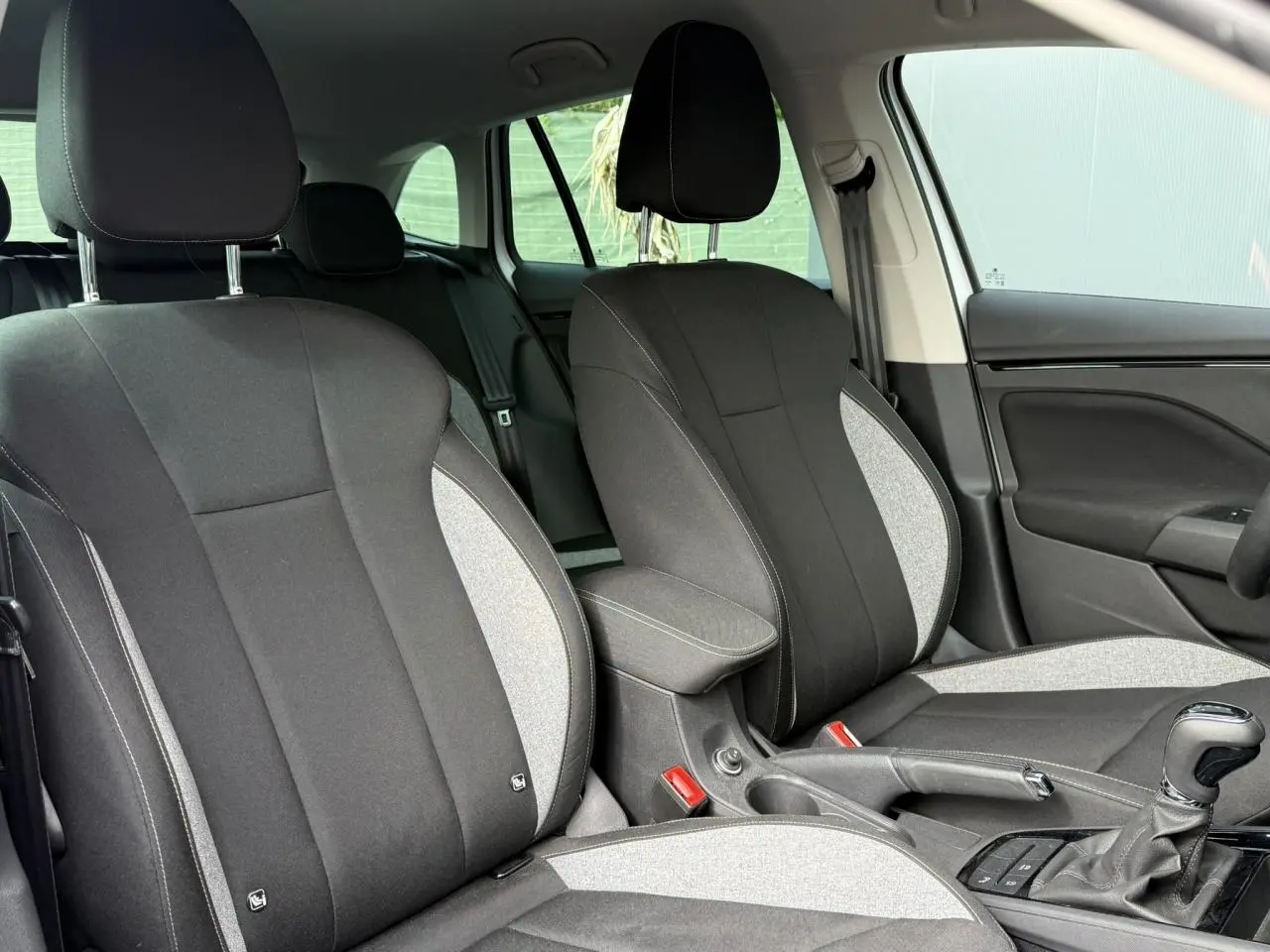 Intérieur de la Skoda Scala TSI 116 DSG7 blanc Glacier, vue rapprochée des sièges avant bicolores noirs et gris.