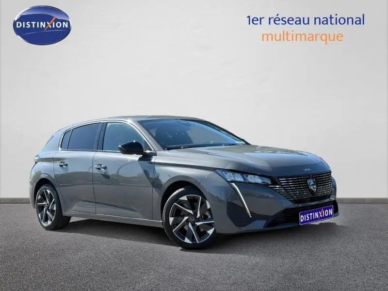 Peugeot 308 gris en 3/4 avant droit, mettant en valeur sa calandre distinctive et ses jantes modernes.