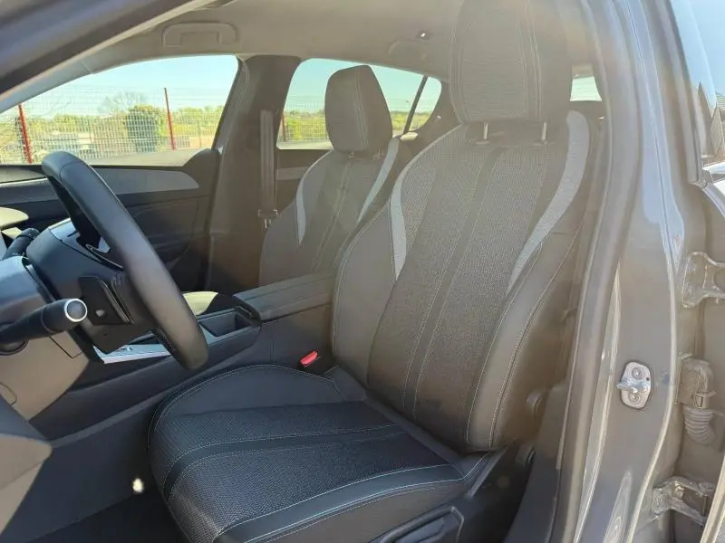 Intérieur de la Peugeot 308 2025 gris, vue côté gauche sur les sièges avant en tissu et cuir avec surpiqûres blanches.