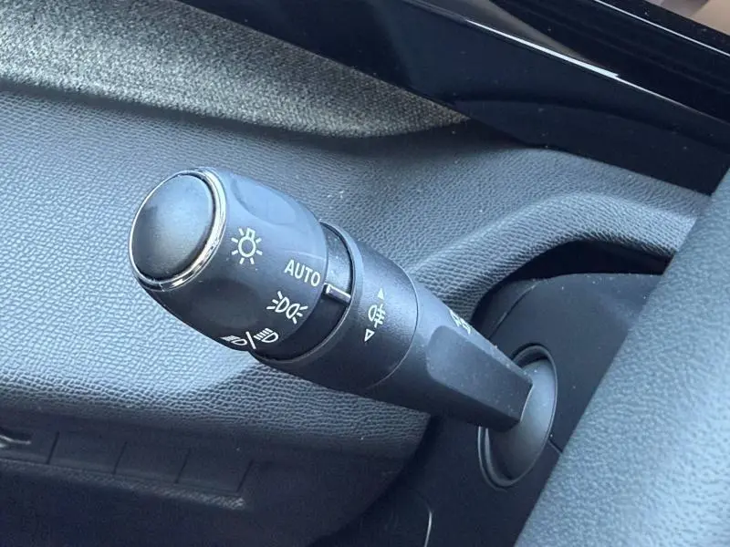 Gros plan sur la commande des feux du Peugeot 308 gris 2025, montrant les réglages automatiques et antibrouillard.
