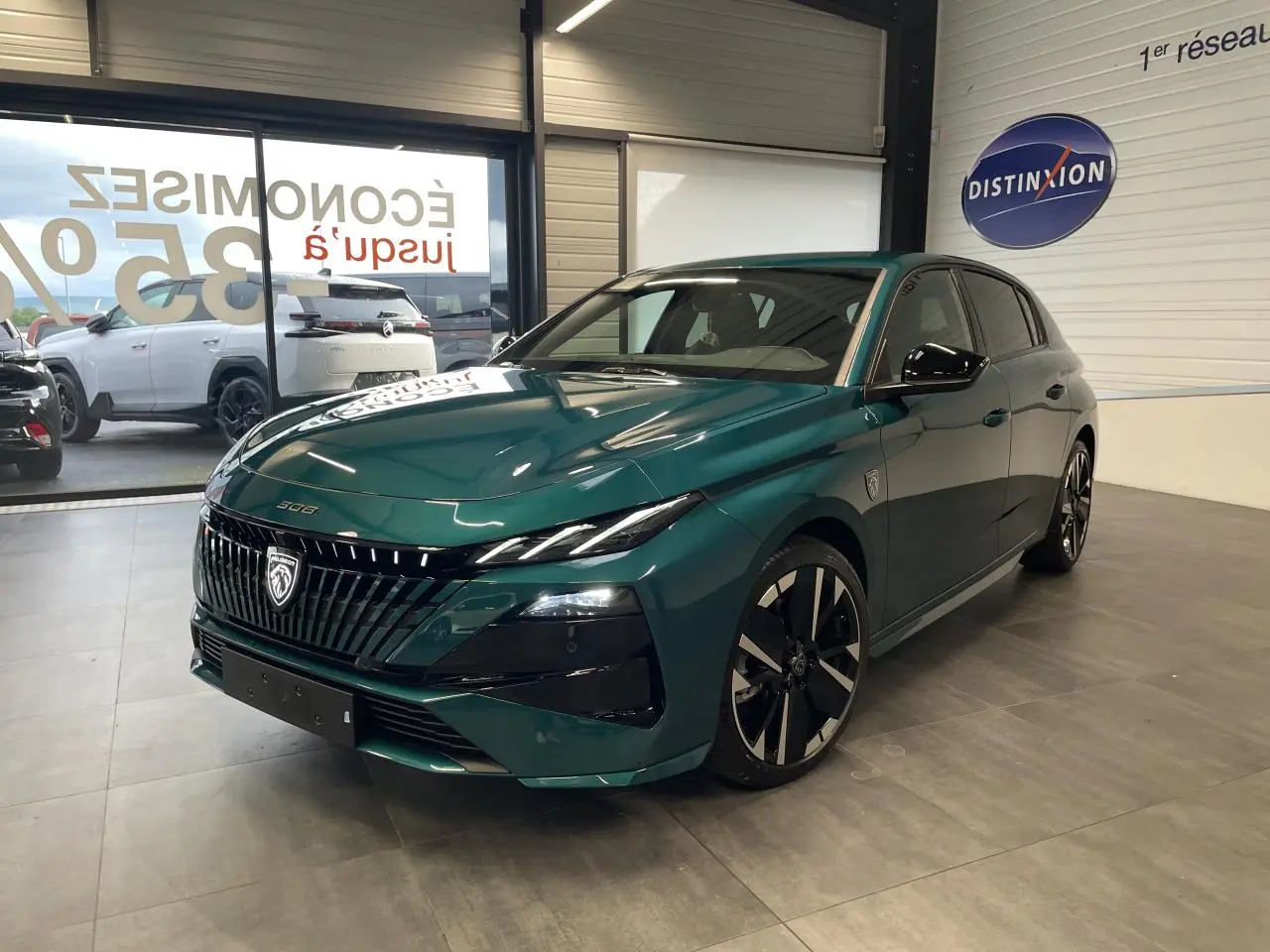 Peugeot 308 GT bleu métallisé vue 3/4 avant droit en intérieur avec calandre noire et jantes bi-tons.
