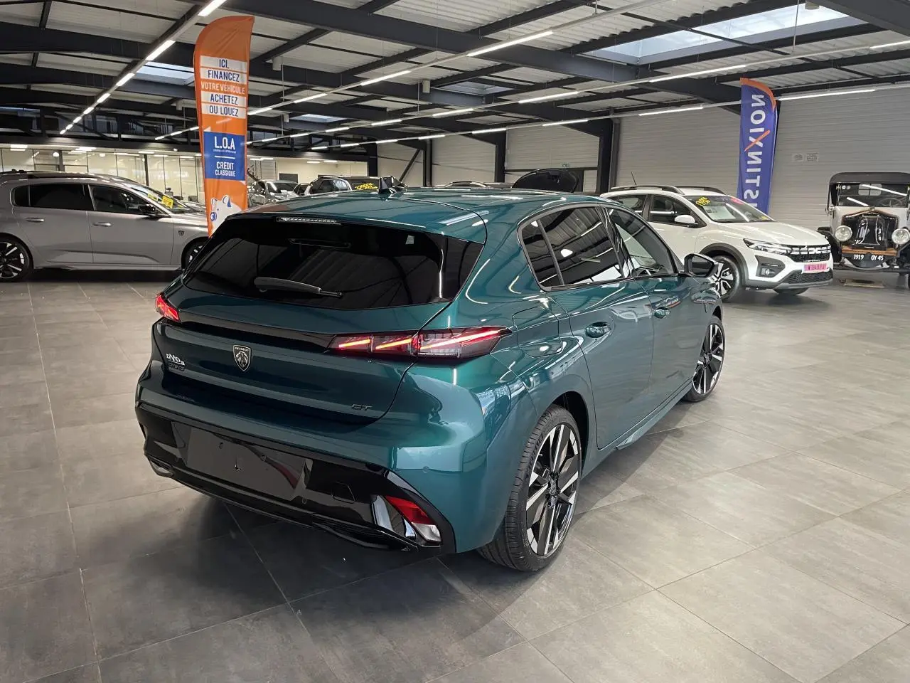 Vue 3/4 arrière droite d'une Peugeot 308 GT bleu métallisé avec jantes alliage bi-tons et feux arrière LED 3 griffes.