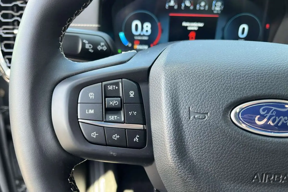 Gros plan sur le volant multifonctions noir du Ford Ranger 2026 avec commandes de régulateur et logo Ford visible.