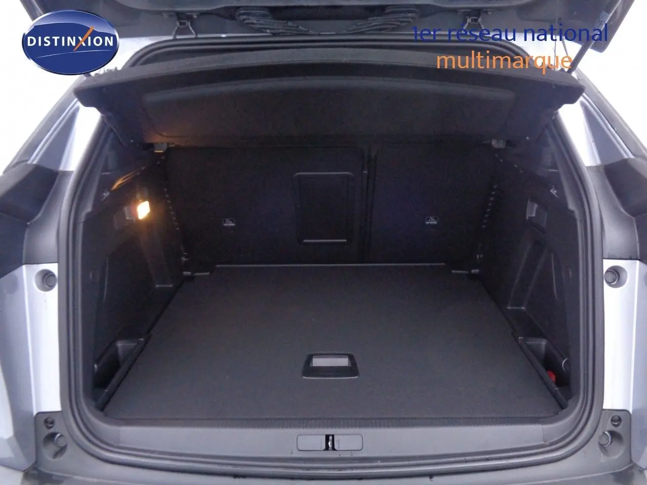 Coffre ouvert d'un Peugeot 3008 gris Artense métal, vue arrière montrant un espace de chargement spacieux et bien éclairé.