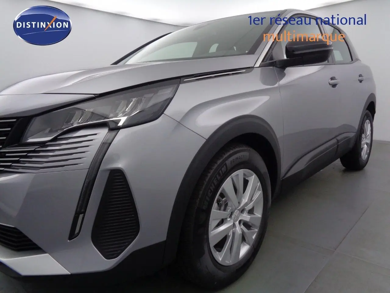 Gros plan sur la roue avant gauche d'un Peugeot 3008 gris Artense métal, avec jante alliage et pneu Michelin.