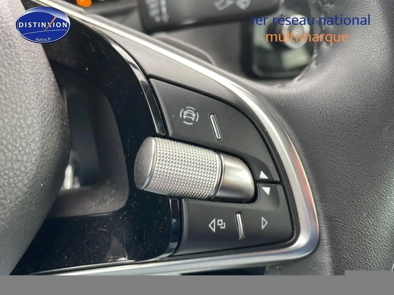 Gros plan sur les commandes multifonctions en métal et plastique noir du volant cuir d’un Skoda Kamiq gris.