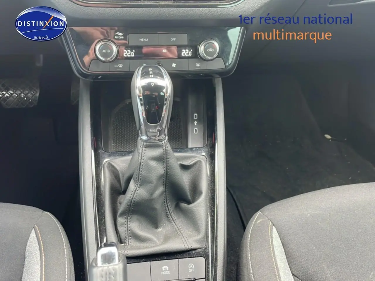 Vue rapprochée de la console centrale avec levier de vitesse automatique et sièges tissu gris du Skoda Kamiq 2025.