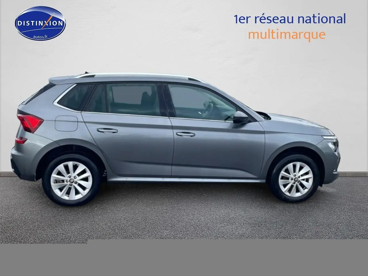 Vue latérale droite d'un Skoda Kamiq gris 2025 avec jantes alliage et barres de toit visibles.