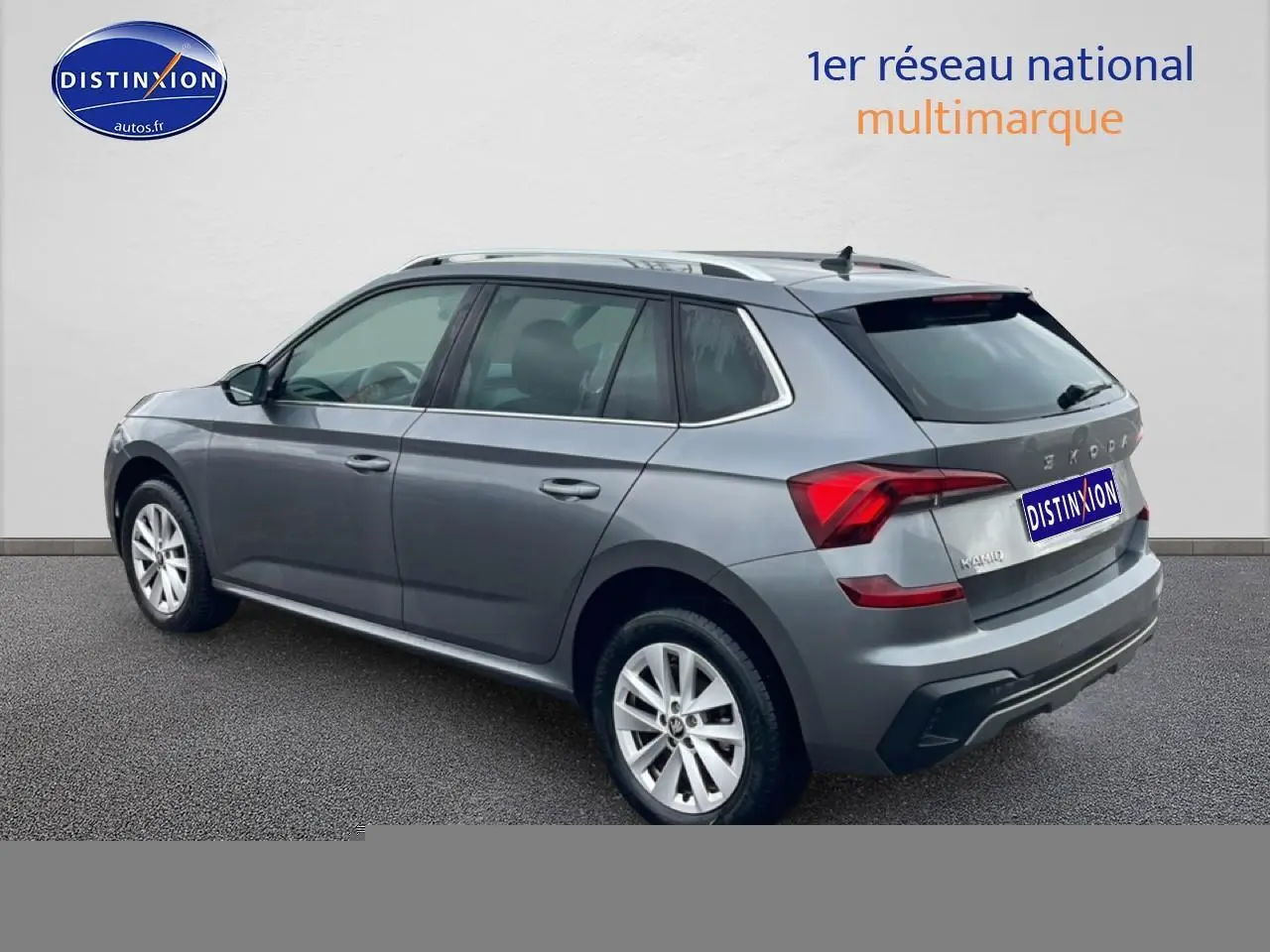 Vue 3/4 arrière droite d'un Skoda Kamiq gris 2025 avec barres de toit et jantes alu visibles.
