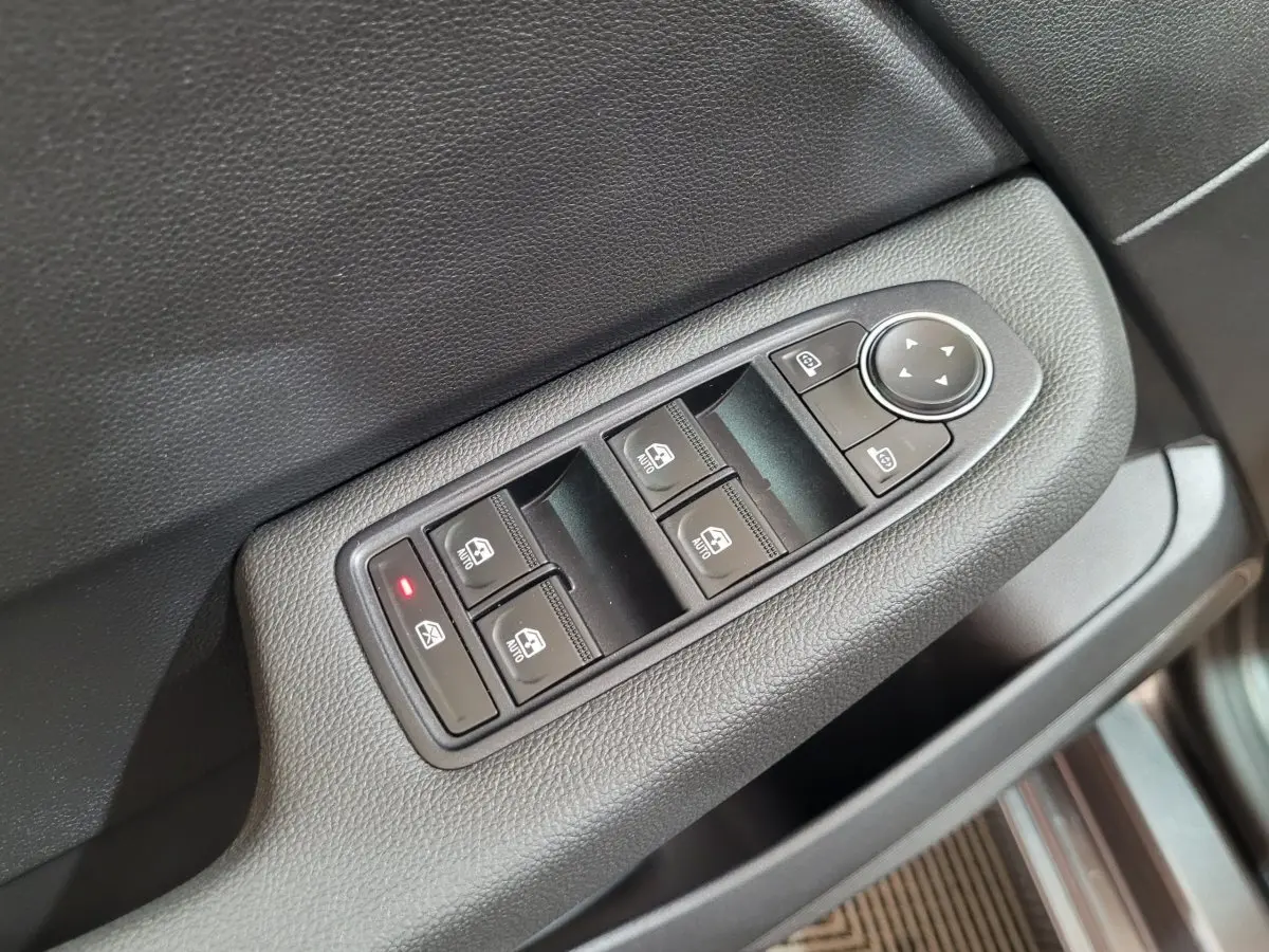 Gros plan sur les commandes de lève-vitres et rétroviseurs côté gauche intérieur d'une Renault Clio gris foncé 2025.