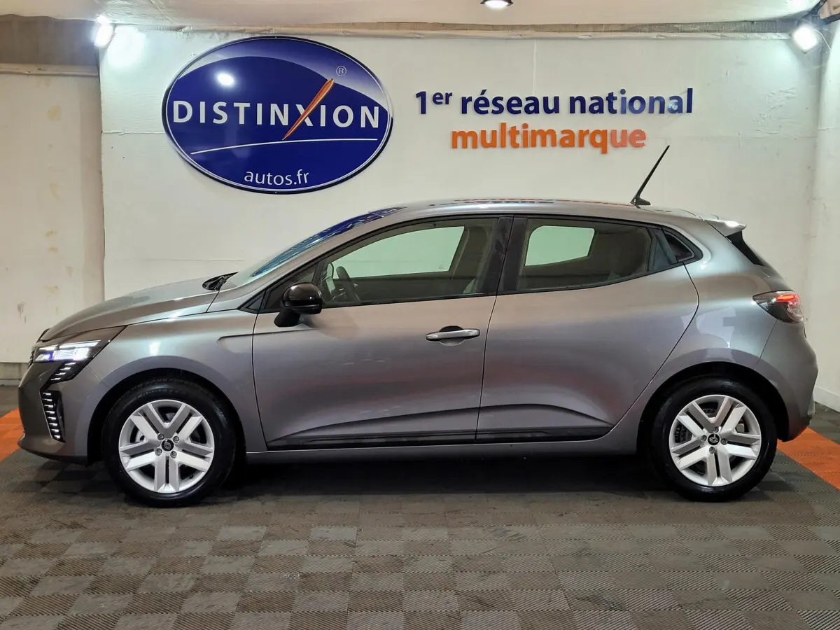 Vue de profil côté gauche d'une Renault Clio gris foncé 2025 dans un showroom avec logo Distinxion en arrière-plan.