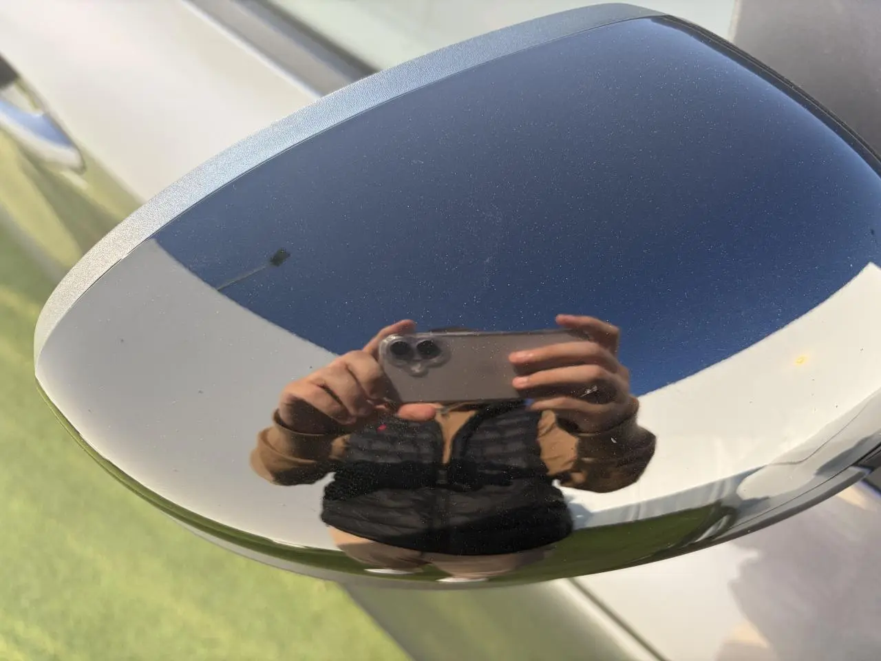 Gros plan sur le rétroviseur droit gris métallisé du Renault Arkana 2025 avec reflet d'une personne prenant la photo.