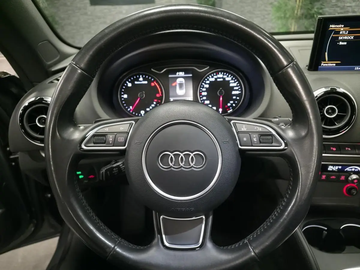 Vue rapprochée du volant cuir noir multifonction Audi A3 Cabriolet 2015 avec tableau de bord et écran MMI visible.