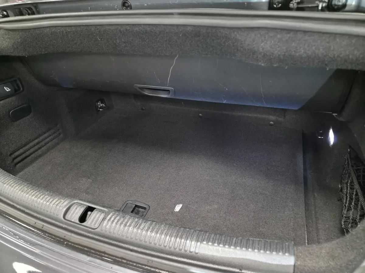 Coffre ouvert de l'Audi A3 Cabriolet gris, montrant l'espace de rangement intérieur avec éclairage latéral.